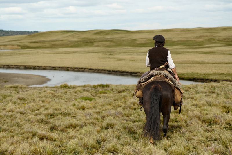 Horse rider next to river in Tierra del Fuego, Patagonia