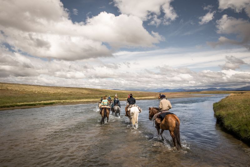 Horse riders in the river in Tierra del Fuego, Patagonia