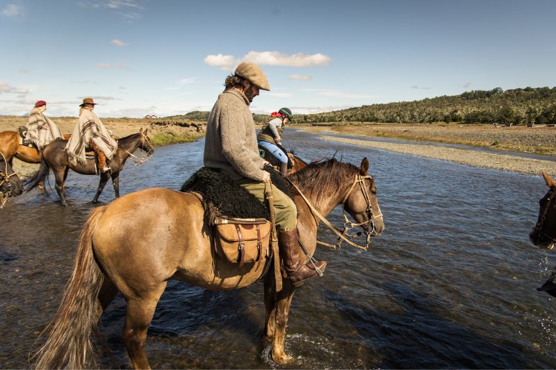 Horse riders crossing river in Tierra del Fuego, Patagonia